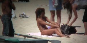 Horny naked brunette woman teasing her mates on the beach