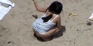 Dark haired woman spied pissing on the beach