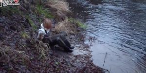Russian Blonde in muddy chest Waders enjoying riverside Mud
