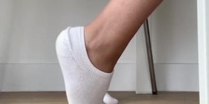 Peek on tanned girl with cute feet in white socks as she works