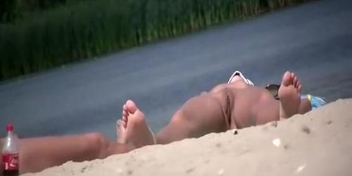 Nudist sunbathing in river shore