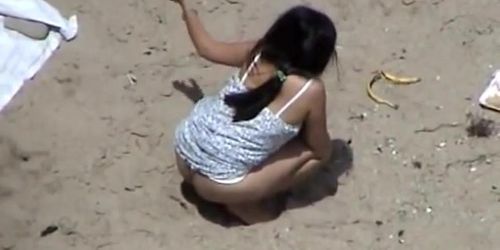 Dark haired woman spied pissing on the beach