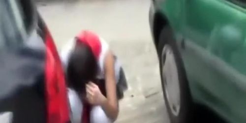 Uniformed girls pissing behind a car