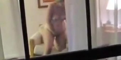 Naked mature woman voyeured masturbating through window