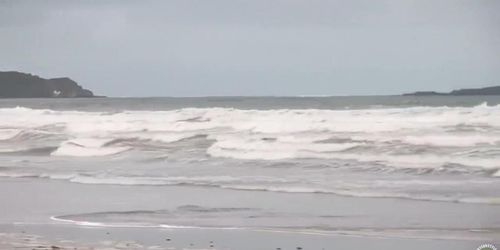 Hundreds of nudist people running into the sea naked