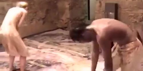 Naked female bodies covered in mud at art show