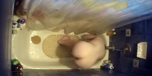 Nude woman bending over in bathtub