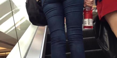 Denim jeans ass going up the escalator