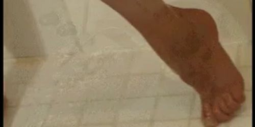 Joven rubia en la ducha usa un rociador para masajear su clítoris y usa un consolador