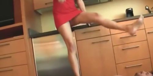 Blonde housewife in red dress tramples her handsome male slave in the kitchen