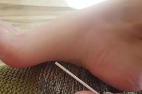 Girl with perfect long feet plays with it with toothpick