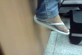 Candid white flip-flops dangling with jeans at class