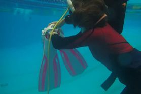 Woman in red wetsuit gears up underwater