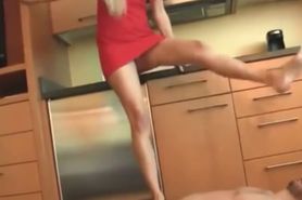 Blonde housewife in red dress tramples her handsome male slave in the kitchen